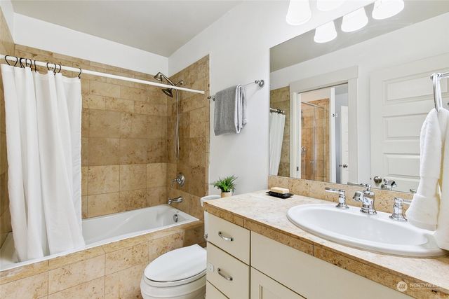 a bathroom with a granite countertop bathtub shower sink vanity mirror and toilet