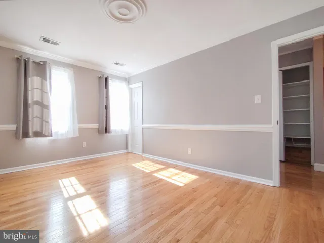 a view of an empty room with wooden floor and closet
