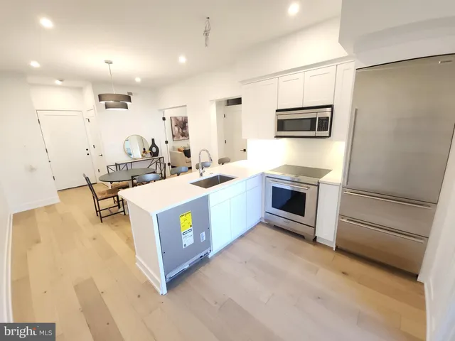 a kitchen with stainless steel appliances a stove a microwave a sink a refrigerator and white cabinets