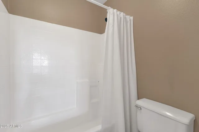 a white toilet sitting next to a shower