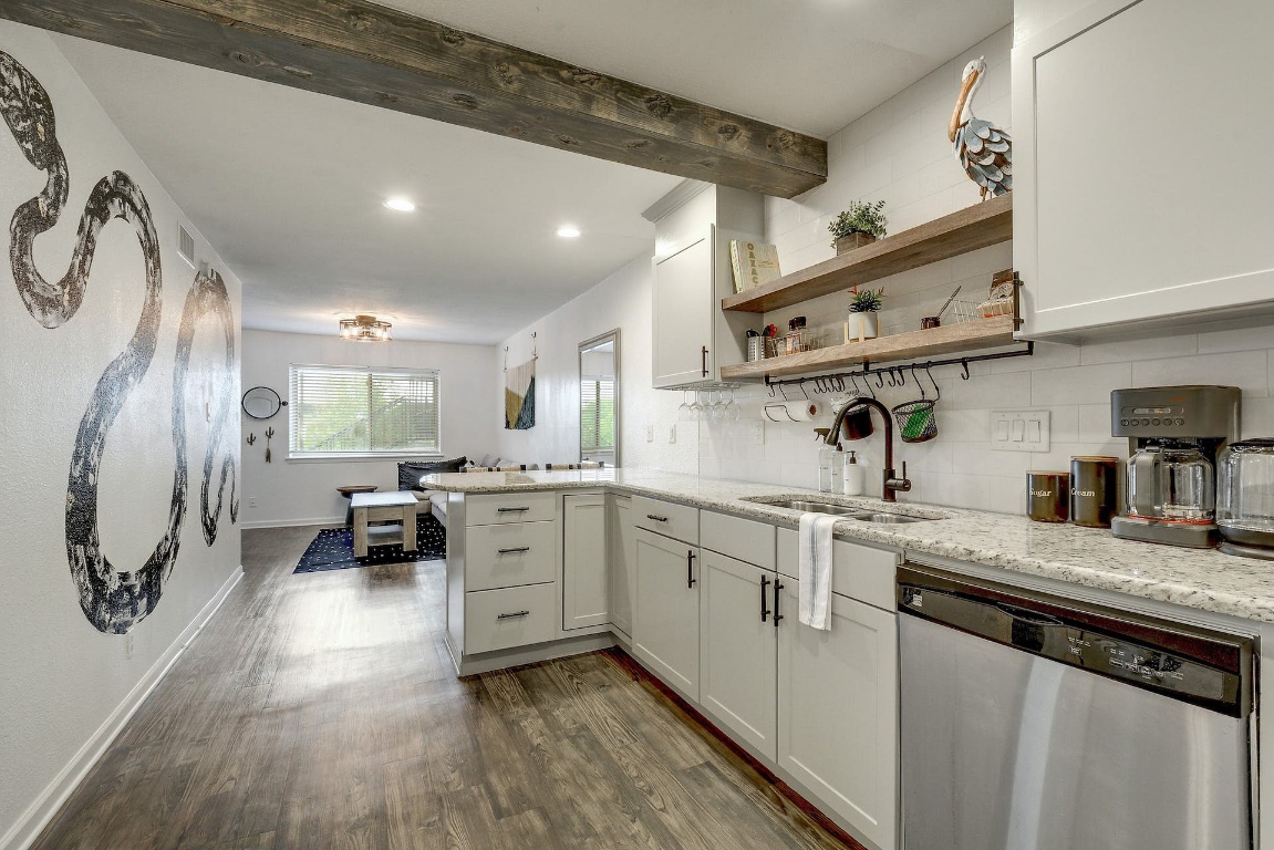 1202 Newning Avenue, Unit 202 Austin, TX 78704 - Photo 12 of 20 Kitchen with open shelves, stainless steel dishwasher, a peninsula, dark wood finished floors, and white cabinets