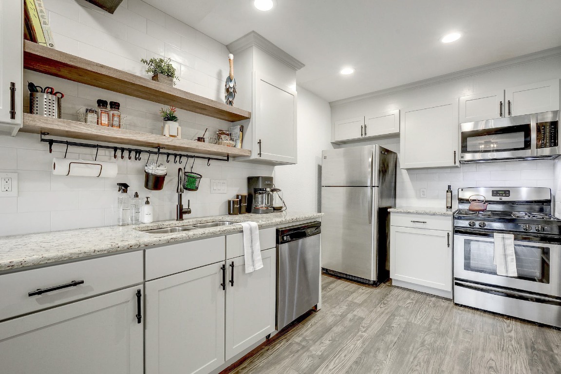 1202 Newning Avenue, Unit 202 Austin, TX 78704 - Photo 4 of 20 Kitchen featuring appliances with stainless steel finishes, tasteful backsplash, light stone countertops, open shelves, and recessed lighting