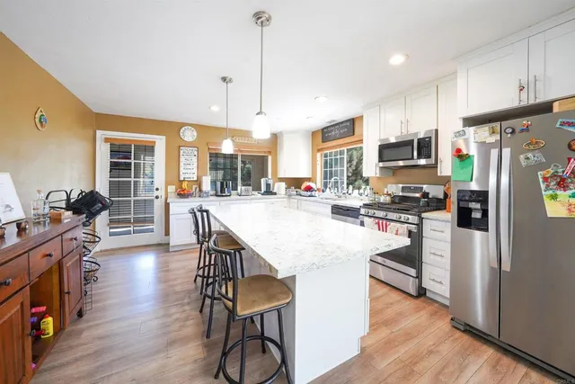 a kitchen with stainless steel appliances a dining table chairs stove refrigerator and cabinets