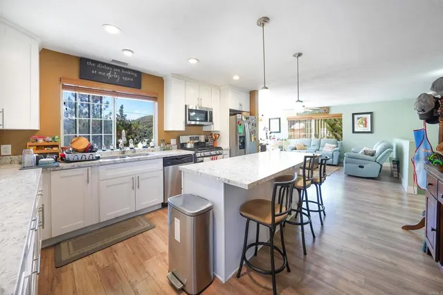 a kitchen with stainless steel appliances a dining table chairs stove and sink