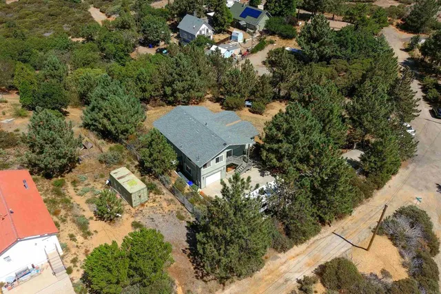 an aerial view of residential houses with outdoor space and trees