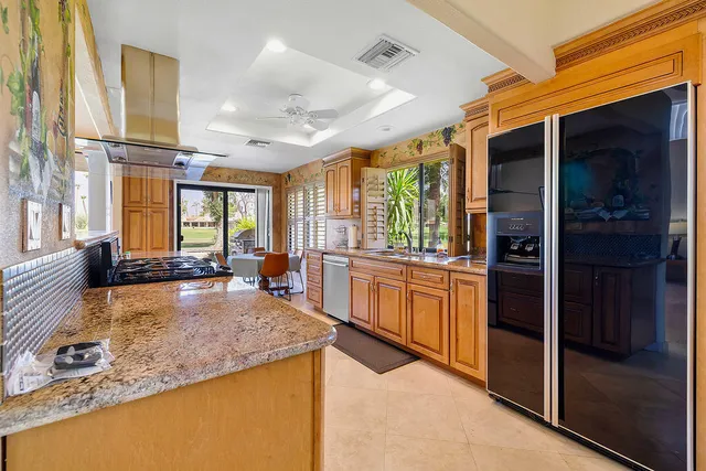 a large kitchen with kitchen island granite countertop a large window and stainless steel appliances