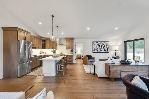 a living room with couches chairs and kitchen view with wooden floor