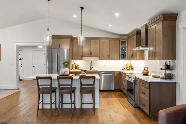 a kitchen with a refrigerator a sink dishwasher and a dining table with wooden floor