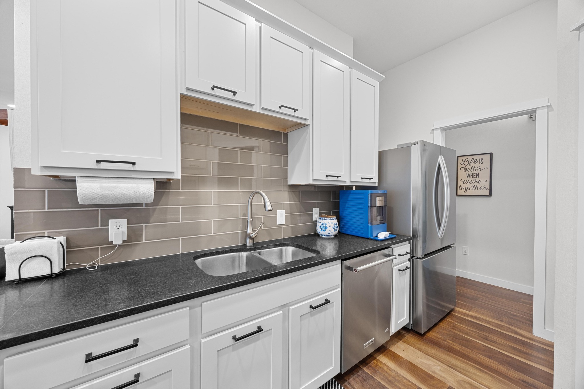 3907 Becker Avenue Austin, TX 78751 - Photo 12 of 37 Kitchen featuring stainless steel appliances, plentiful white cabinets, wood floors, decorative backsplash, and dark honed granite counters.
