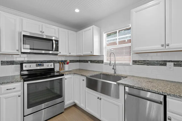 a kitchen with granite countertop white cabinets white stainless steel appliances and a sink