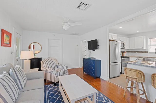 a living room with furniture a flat screen tv and kitchen view