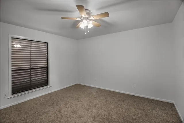 an empty room with a chandelier fan and windows