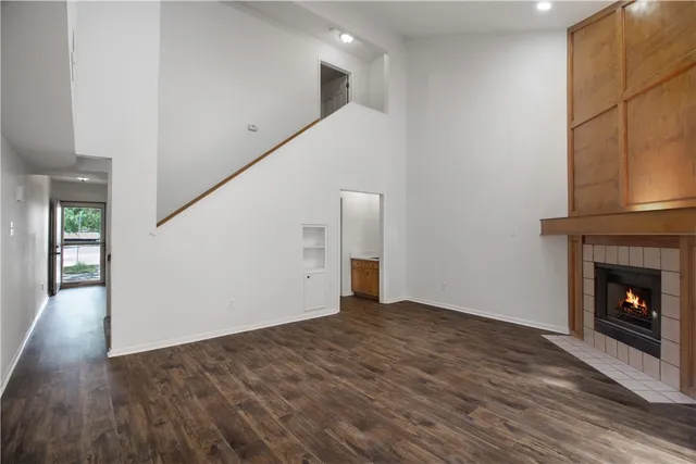 a view of an empty room with wooden floor and a fireplace