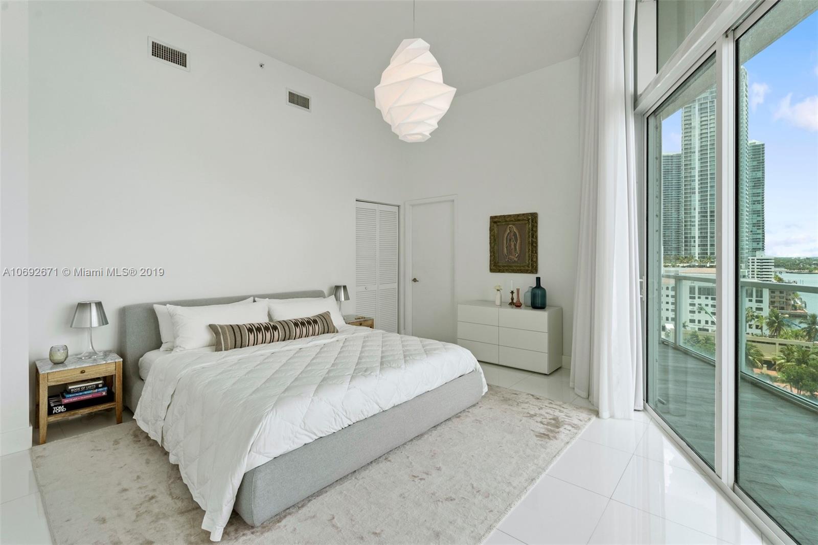 665 Northeast 25th Street, Unit 802 Miami, FL 33137 - Photo 11 of 24 a bedroom with a large bed and a chandelier