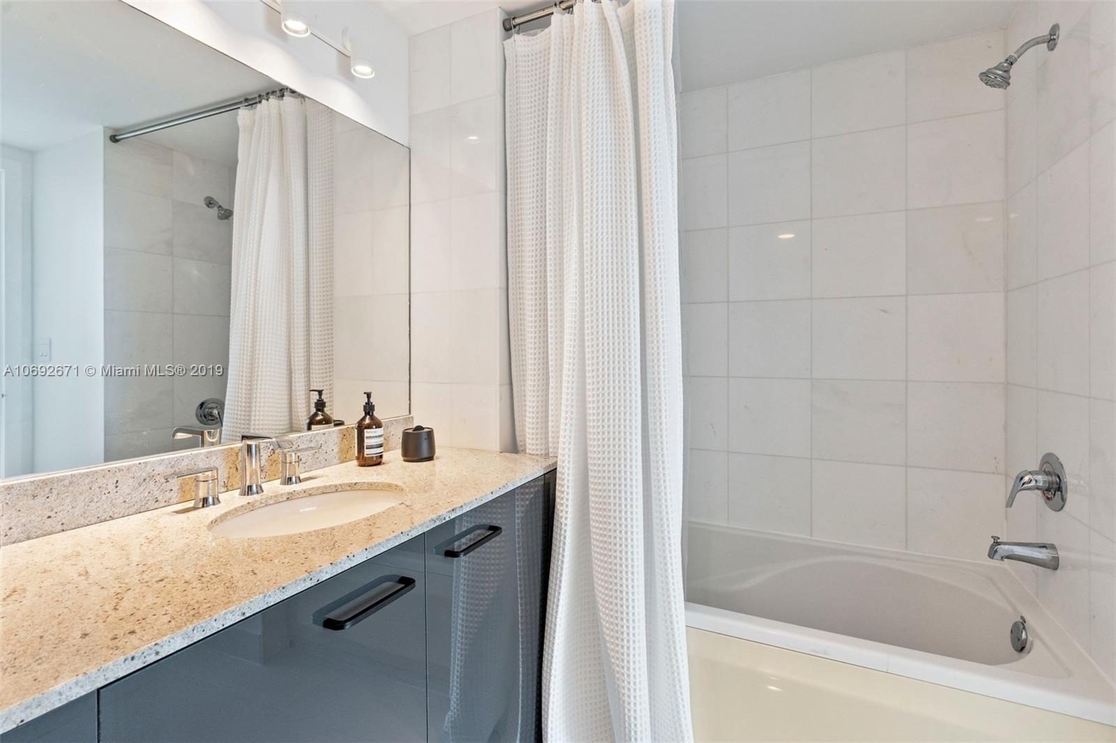 665 Northeast 25th Street, Unit 802 Miami, FL 33137 - Photo 15 of 24 a bathroom with a bathtub sink vanity and mirror