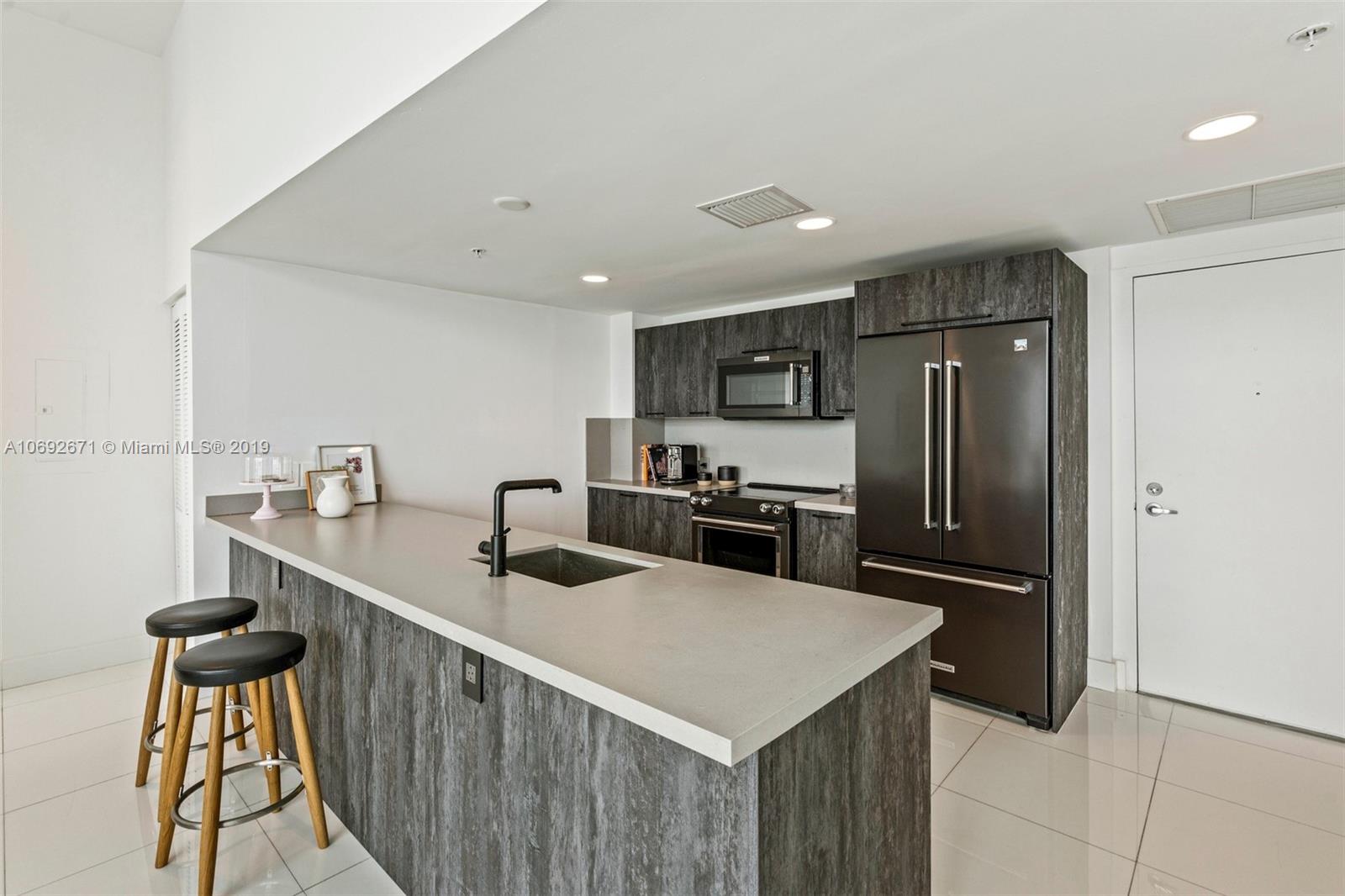 665 Northeast 25th Street, Unit 802 Miami, FL 33137 - Photo 6 of 24 a kitchen that has a sink a refrigerator and cabinets