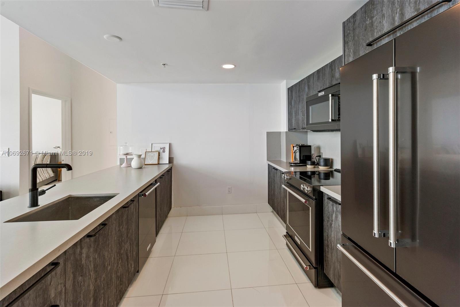 665 Northeast 25th Street, Unit 802 Miami, FL 33137 - Photo 8 of 24 a kitchen with granite countertop a refrigerator and a sink