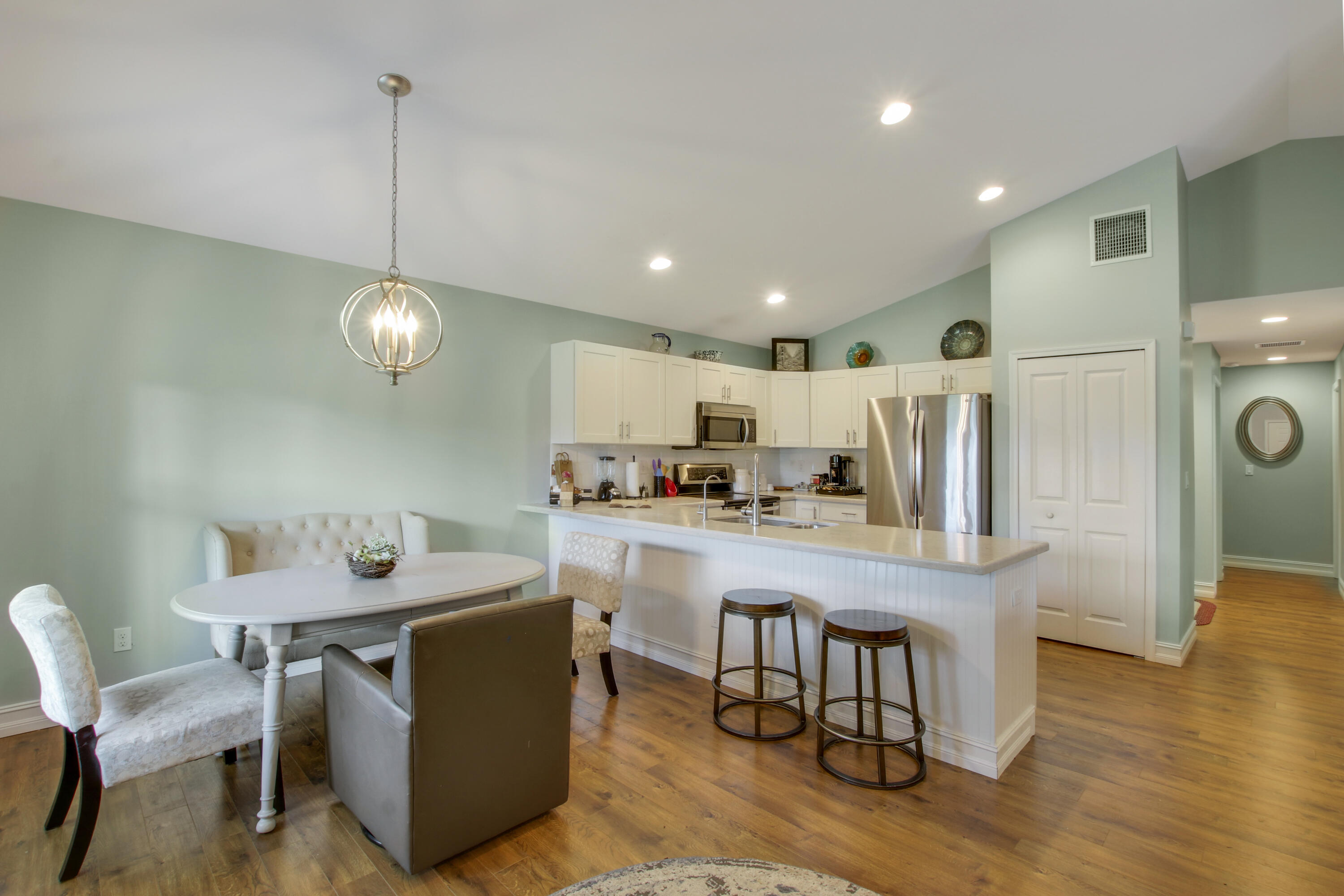 9155 Southeast Athena Street Hobe Sound, FL 33455 - Photo 8 of 25 a kitchen with a dining table chairs refrigerator and cabinets