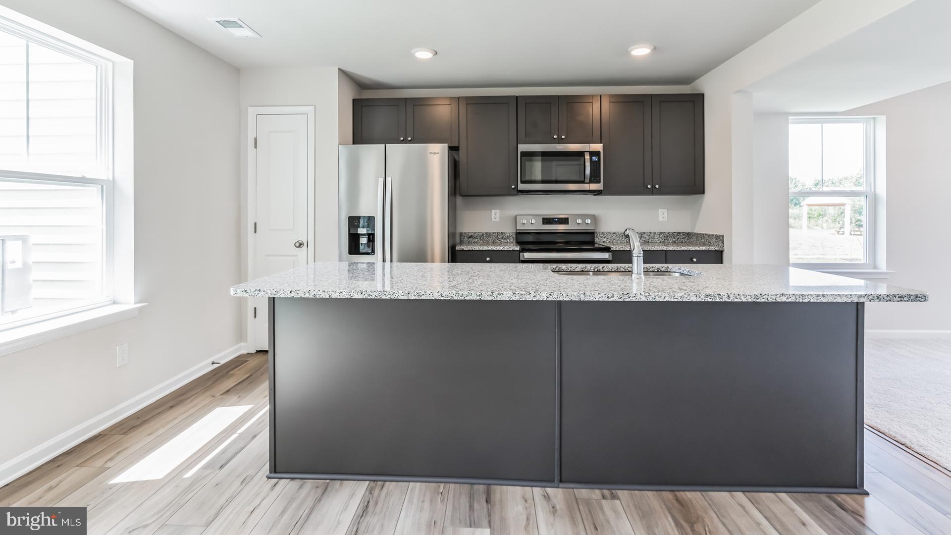 601 Widgeon Way Cambridge, MD 21613 - Photo 3 of 17 a kitchen with granite countertop a refrigerator a sink a stove a microwave a counter space and cabinets