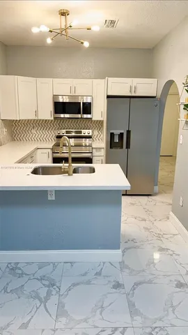 a kitchen with stainless steel appliances a refrigerator a stove a sink and a oven