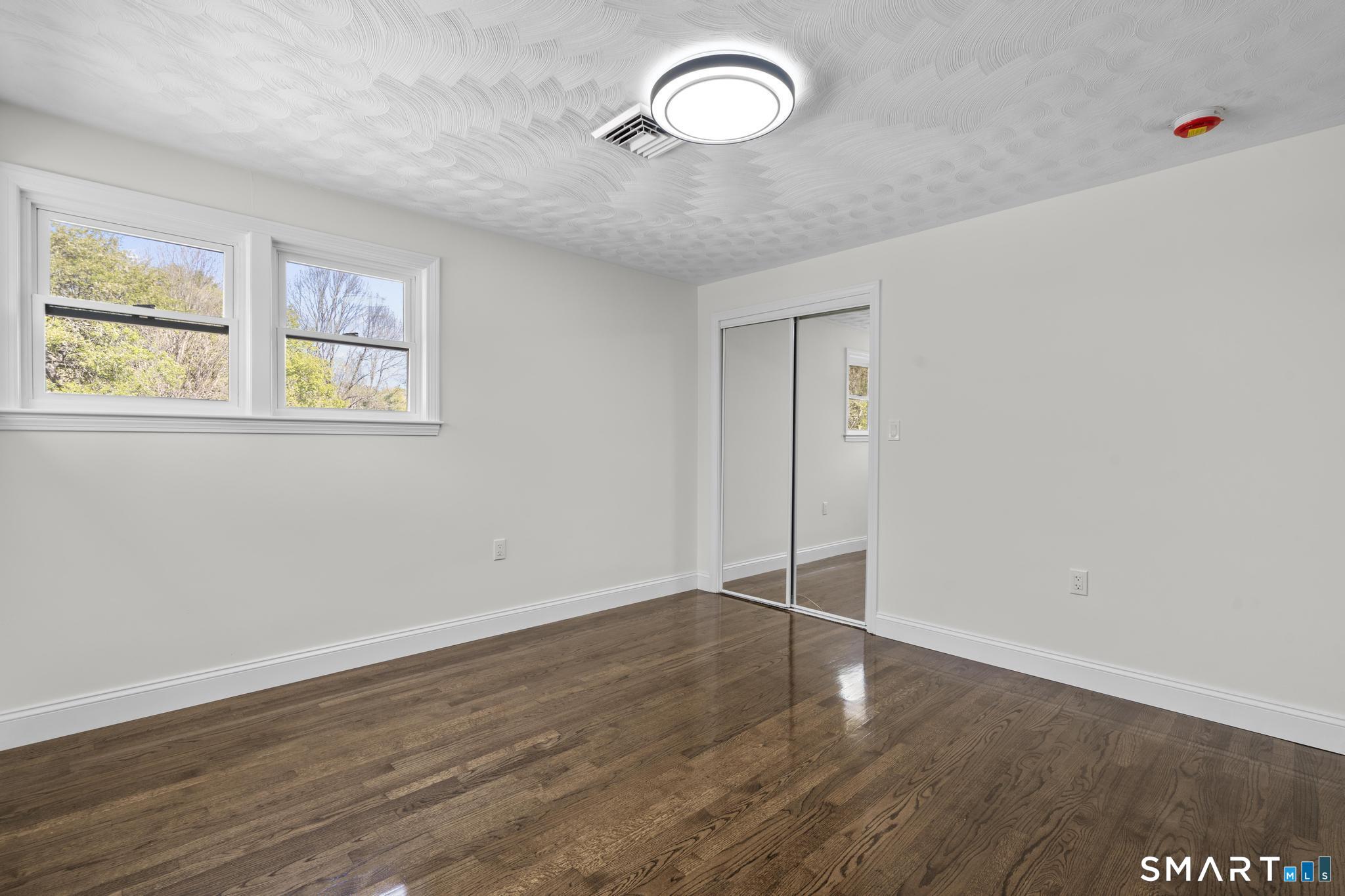 26 Quaddick Town Farm Road Thompson, CT 06277 - Photo 18 of 32 an empty room with wooden floor and windows