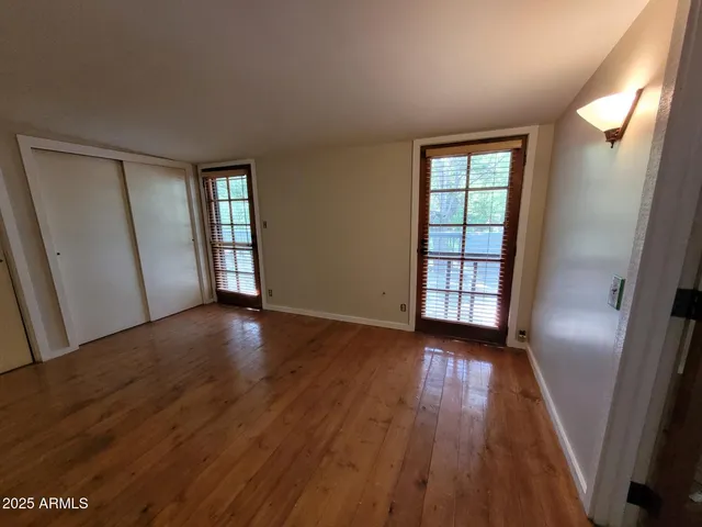 an empty room with wooden floor and windows