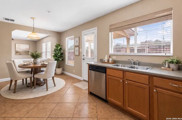 a dining hall with stainless steel appliances granite countertop a stove a sink a dining table and chairs