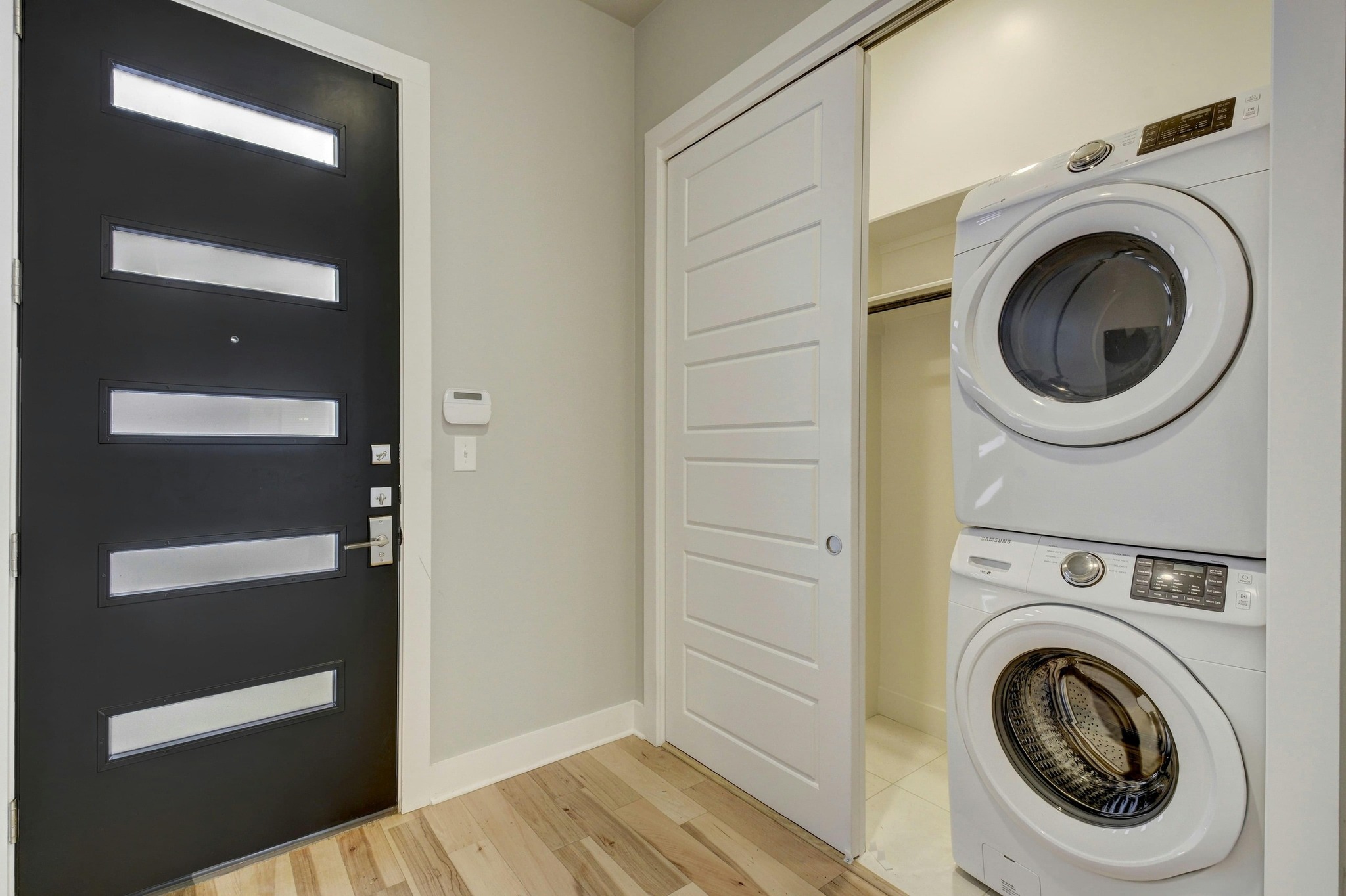 2314 Enfield Road, Unit 202 Austin, TX 78703 - Photo 17 of 20 Indoor/private laundry facilities are IN UNIT and integrate seamlessly with a contemporary entry, featuring light hardwood flooring.