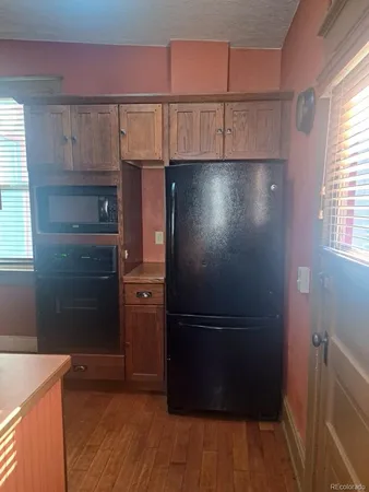 a kitchen with a refrigerator and wooden floor
