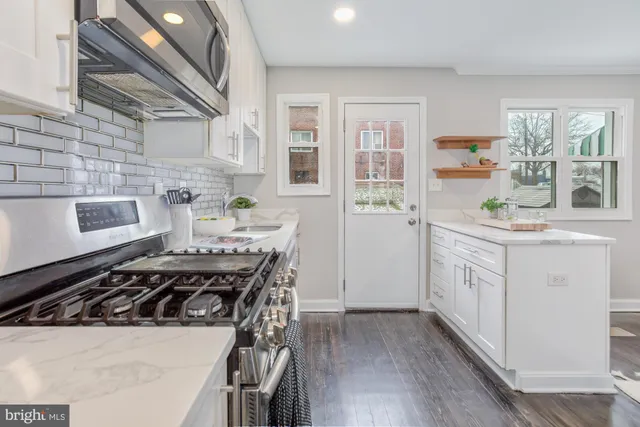 a kitchen with a stove a sink and wooden floor