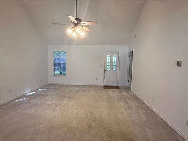 an empty room with windows and chandelier fan