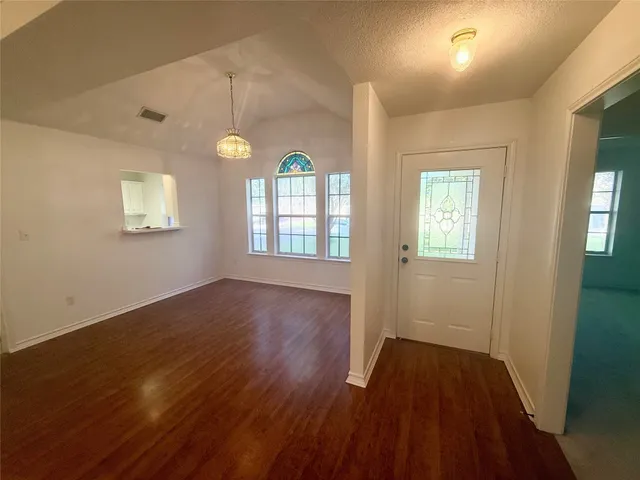 an empty room with an entryway and chandelier fan