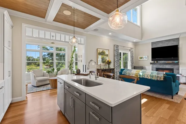 a view of living room kitchen with stainless steel appliances granite countertop a stove a kitchen island a couch and a flat screen tv