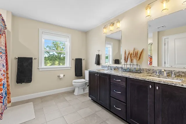 a bathroom with a granite countertop sink toilet and mirror