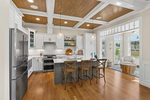 a kitchen with stainless steel appliances granite countertop a stove top oven a refrigerator a dining table and chairs with wooden floor