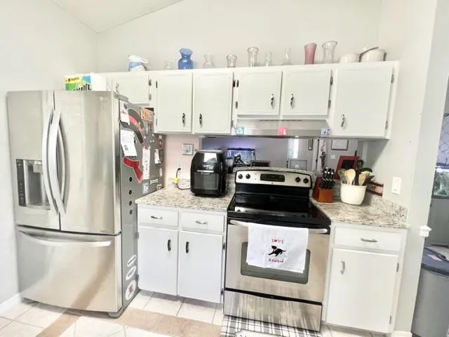 a kitchen with stainless steel appliances granite countertop a refrigerator sink stove and white cabinets