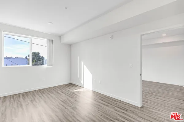 a view of an empty room with wooden floor and a window