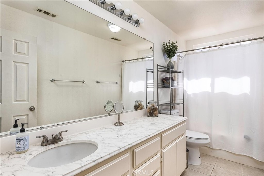 42064 Pine Needle Street Temecula, CA 92591 - Photo 22 of 39 a bathroom with a granite countertop sink a toilet and a mirror