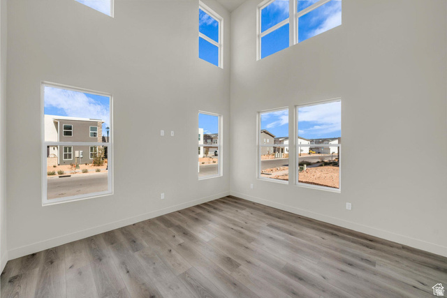 560 Aqua Cove St. George, UT 84790 - Photo 7 of 27 Unfurnished living room featuring light wood-style flooring, a high ceiling, and plenty of natural light