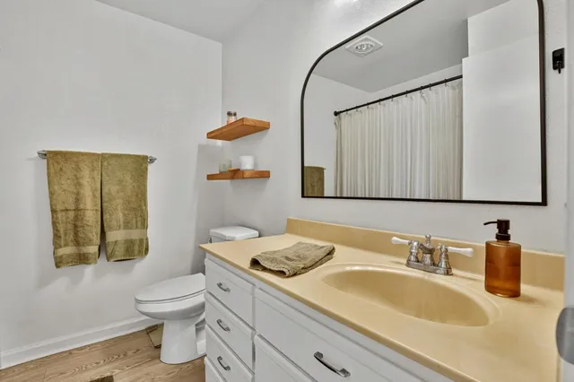 a bathroom with a granite countertop sink mirror vanity and toilet
