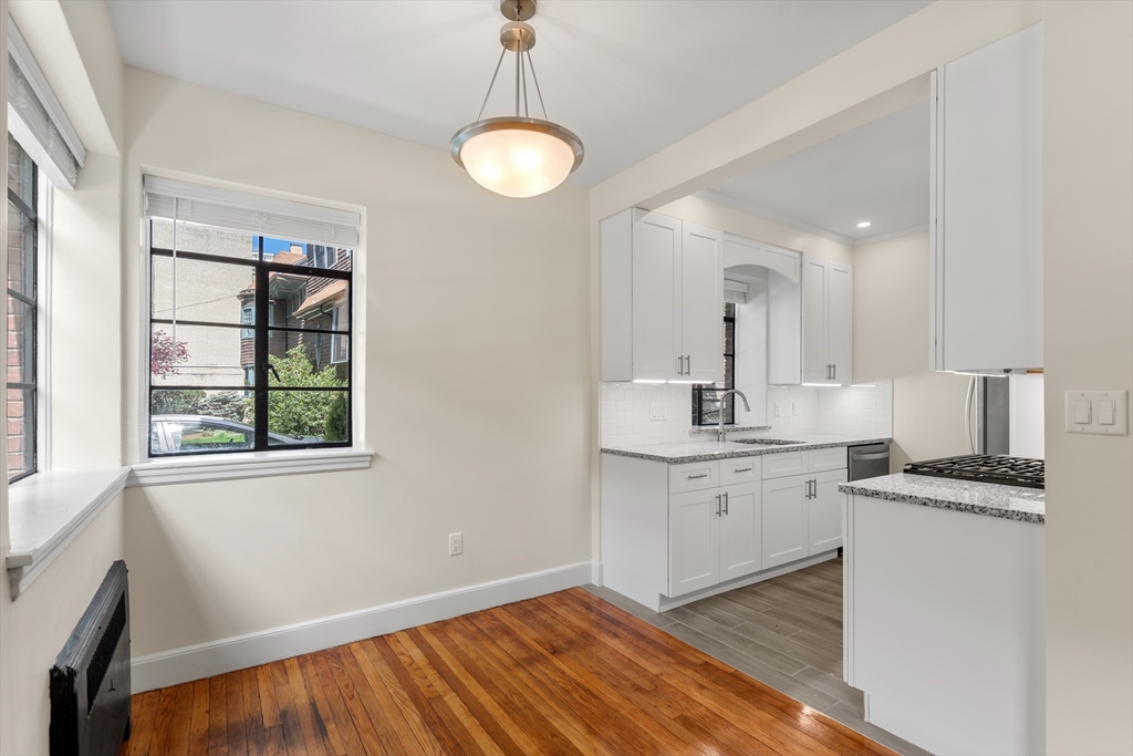 97 Strathmore Road, Unit 1 Boston, MA 02135 - Photo 4 of 16 a kitchen with granite countertop white cabinets and white appliances