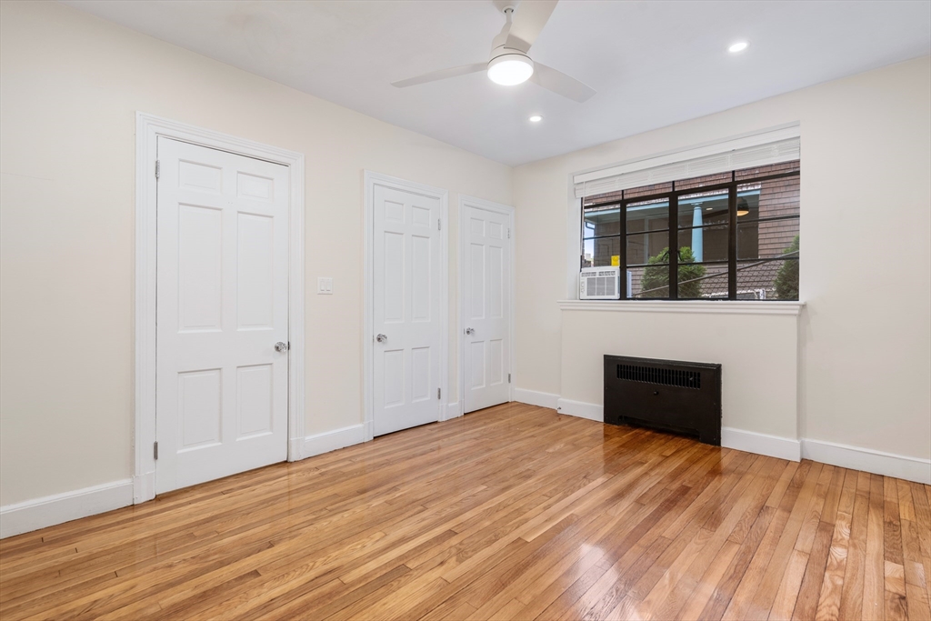 97 Strathmore Road, Unit 1 Boston, MA 02135 - Photo 8 of 16 an empty room with wooden floor cabinet and windows