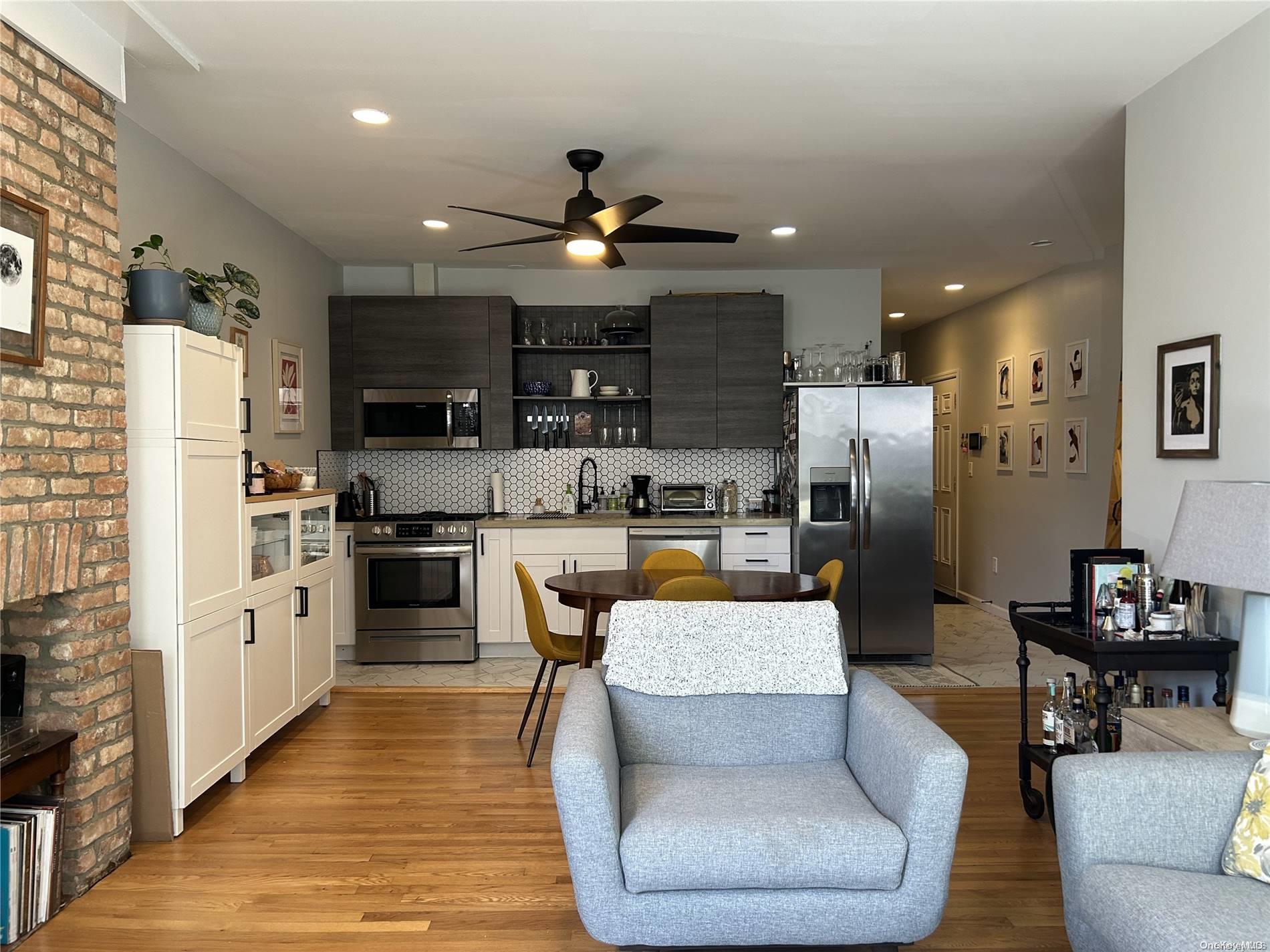 a living room with stainless steel appliances furniture fireplace and open kitchen view