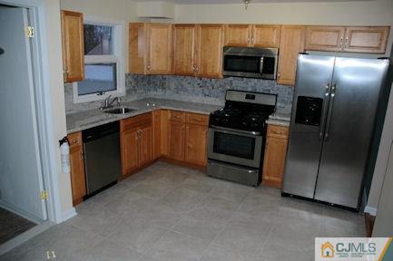 10 Maple Road Iselin, NJ 08830 - Photo 4 of 15 a kitchen with stainless steel appliances granite countertop a stove a sink and a refrigerator