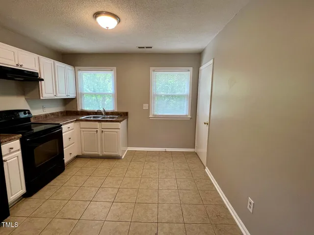 a kitchen with a sink a stove top oven and cabinets
