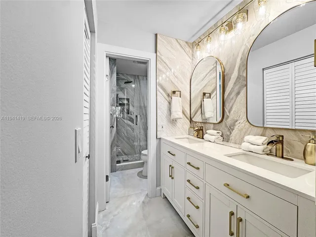a bathroom with a double vanity sink mirror and shower