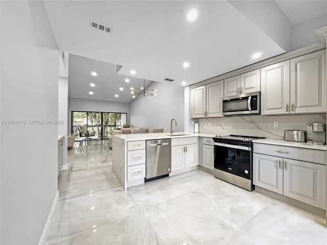 a large white kitchen with a sink a stove a microwave and cabinets