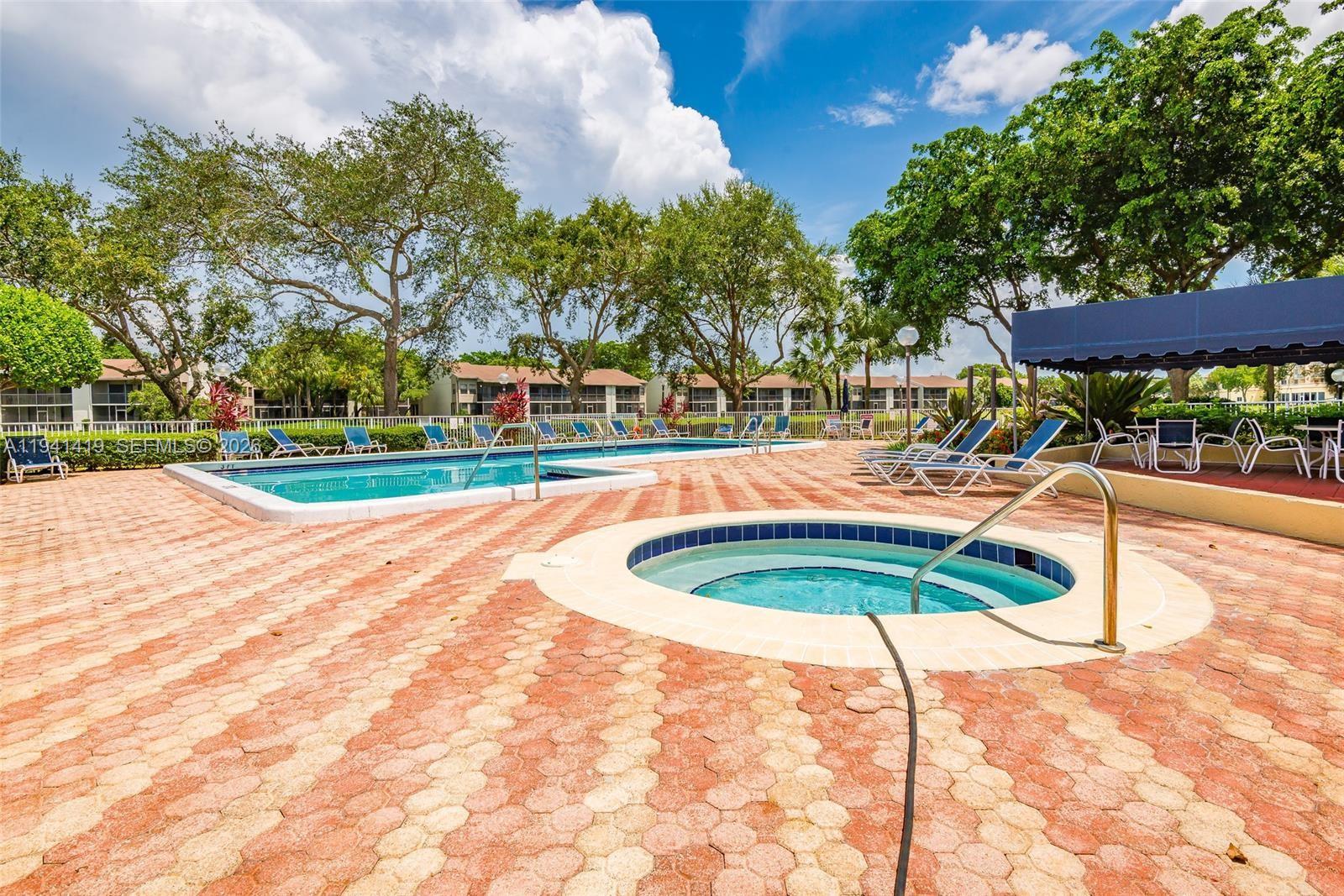 1977 Southwest 15th Street, Unit 116 Deerfield Beach, FL 33442 - Photo 29 of 37 a small pool with lawn chairs and plants