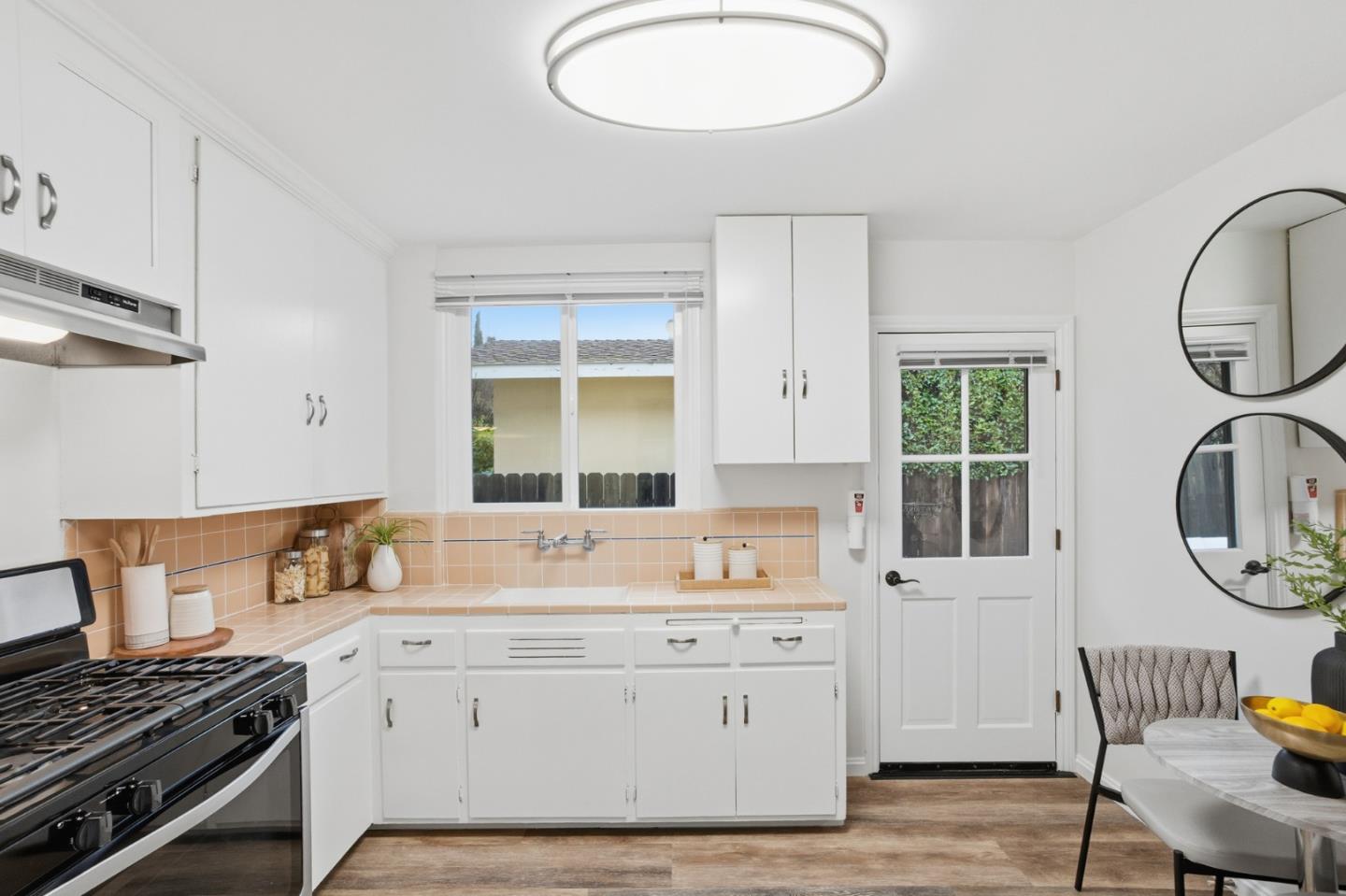 200 Anita Road Burlingame, CA 94010 - Photo 11 of 50 a kitchen with granite countertop a stove a sink and a dining table with wooden cabinet