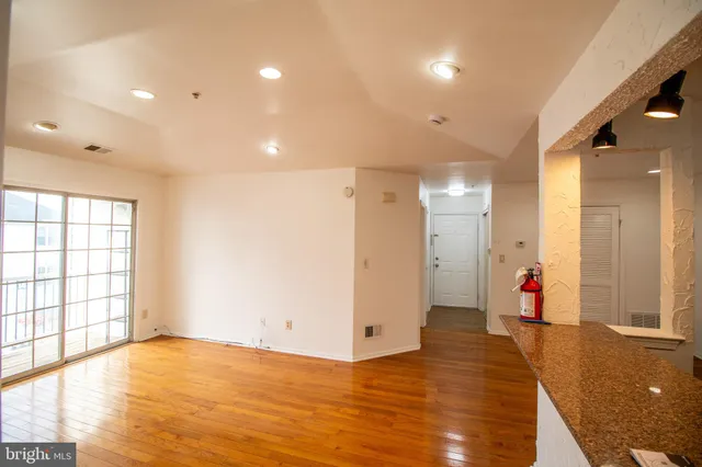 a view of an empty room with wooden floor and windows